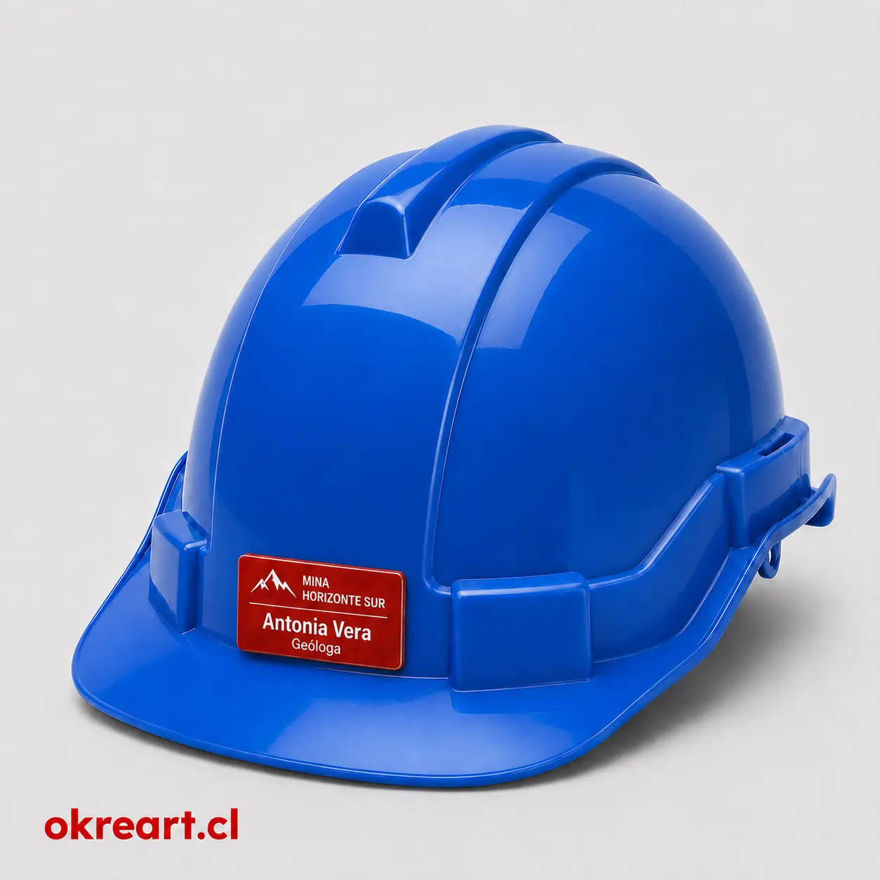 Placa roja para casco de seguridad de 6x3 cm en casco azul, vista ladeada, personalizada con nombre y cargo.