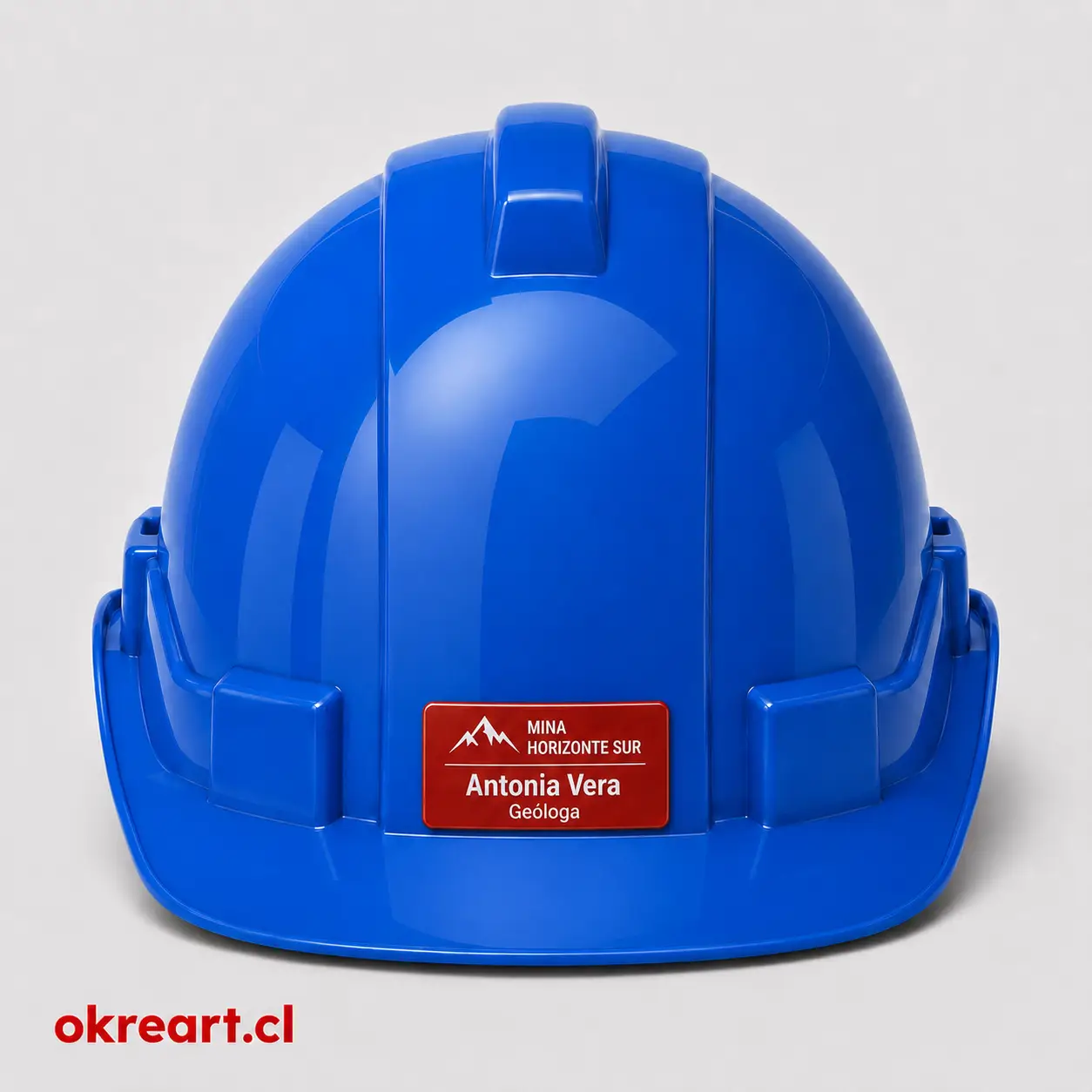 Placa roja para casco de seguridad de 6x3 cm en casco azul, vista frontal, personalizada con nombre y cargo.
